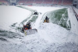 sneeuwschuiven en sneeuwvrij maken kunstgrasveld
